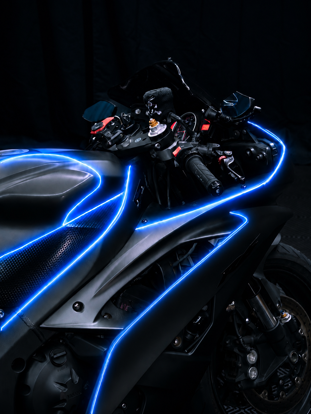 Close-up of a sport bike's tank and cockpit at night, blue NYTRON contour lighting tracing the panel edges.